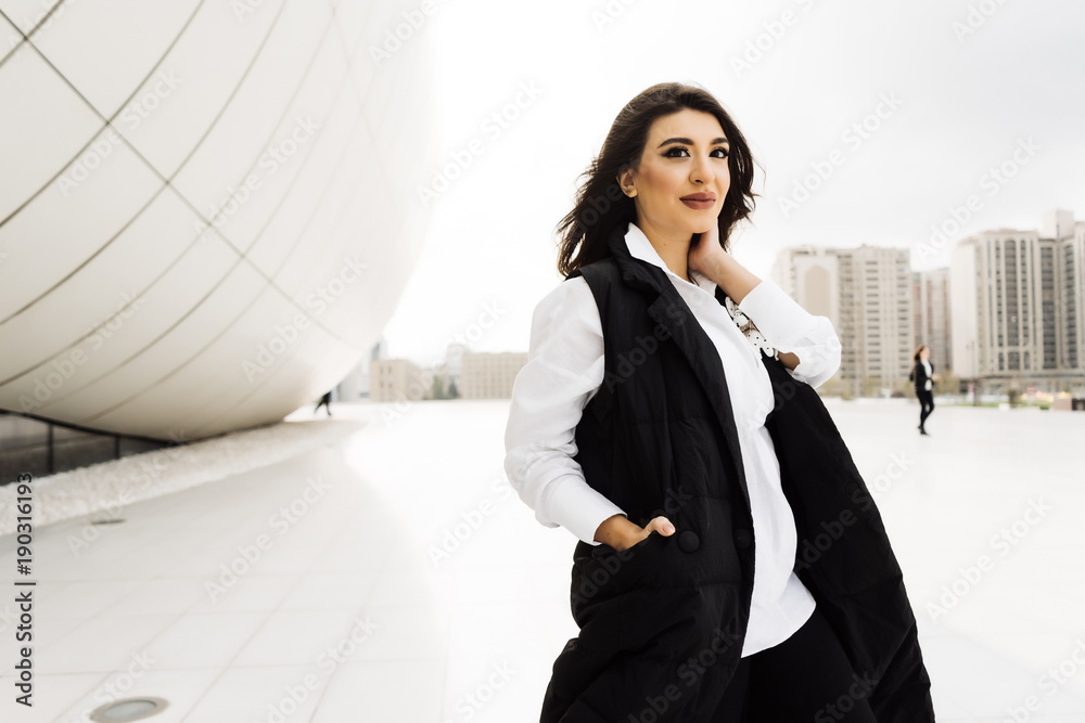 stylish young woman in a black suit posing against the background of ...