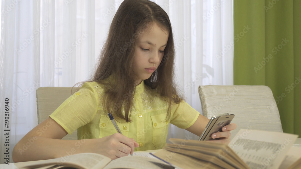 Teenager girl does homework with smartphone Teenager girl does homework with smartphone