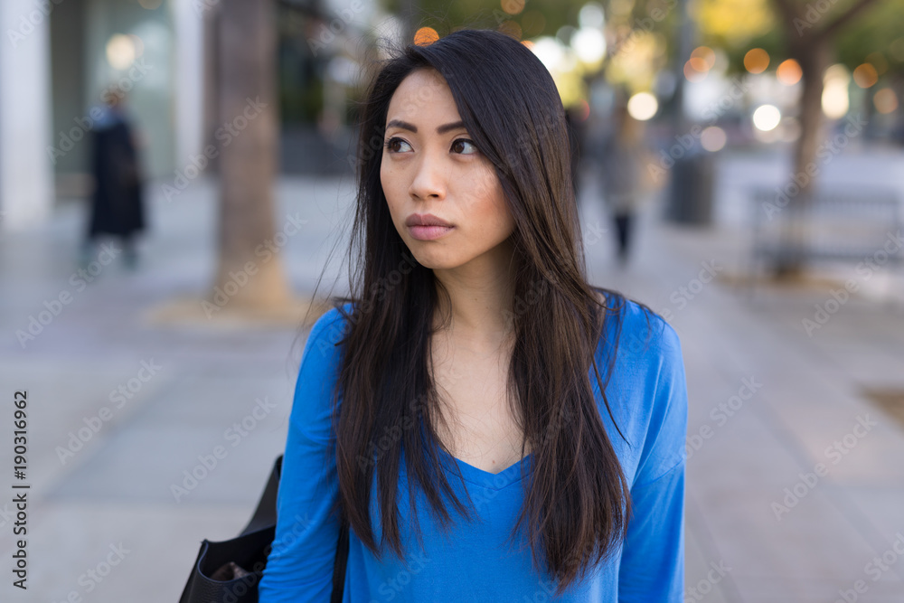Young Asian woman walking street sad