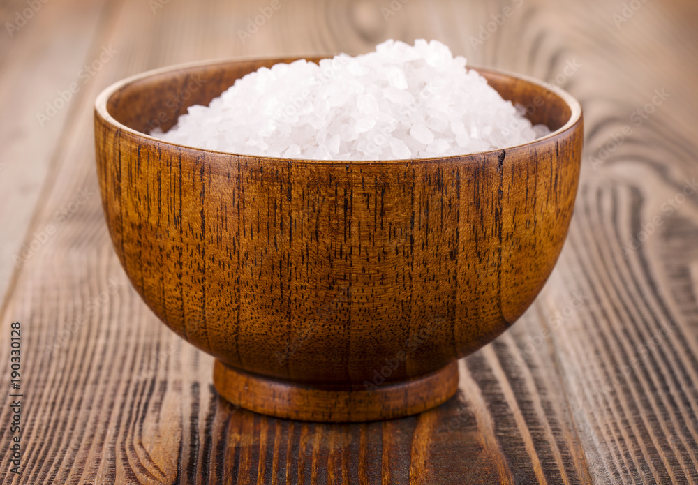 white bath salt in a wooden Cup on wooden surface white bath salt in a wooden Cup on wooden surface