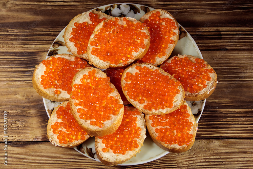 Sandwiches with butter and red caviar on wooden table Sandwiches with butter and red caviar on wooden table