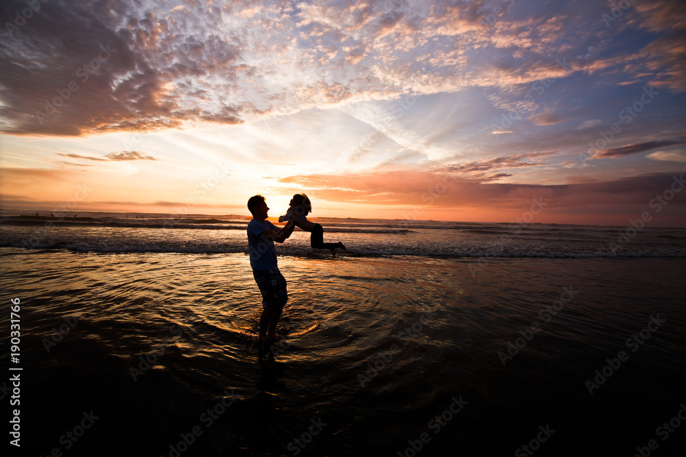 Silhouette of father  playing with daughter on the beach at the sunset time. Outdoor and friendly family concept. Vacation Time, Pacific Ocean, Sea Side Oregon USA