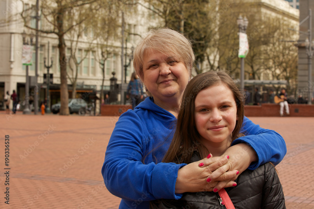 Obraz premium Close-up Portrait of Happy grandmother Hugging her Ten Years old Granddaughter staying in the middle of Downtown Portland Oregon USA, Happy Family Concept