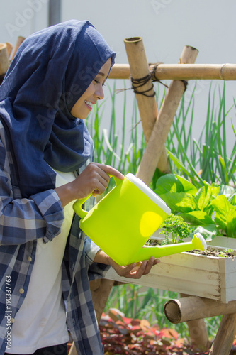 happy muslim woman watering her garden