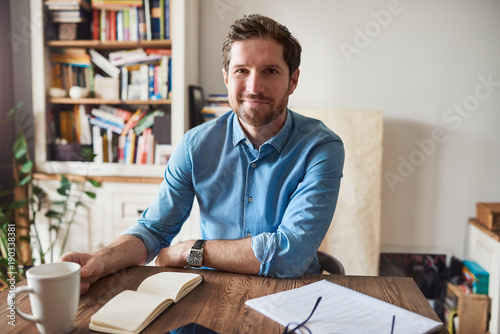 Fotografi Smiling man working at his living room table at home