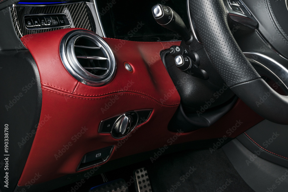 AC Ventilation Deck in Luxury modern Car Interior. Modern car interior details with red and black leatherwith red stitchin. Carbon panel. Perforated leather steering wheel