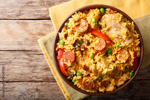 Arroz Valenciana with rice, meat, sausage, raisins, vegetables and spices close up in a bowl. horizontal top view