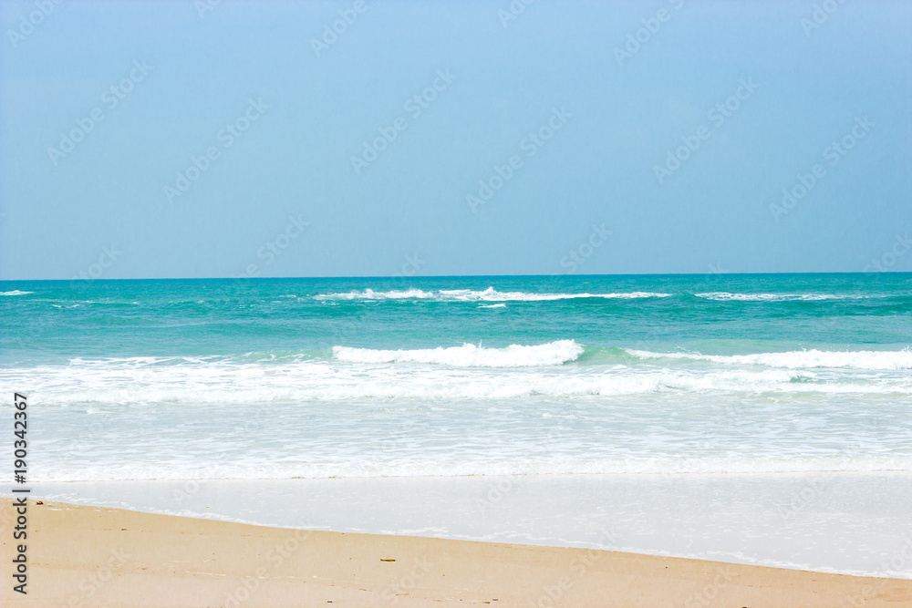 waves with foam of blue ocean on the sandy beach