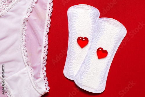 Menstruation. White panties and pads liners on red background photo