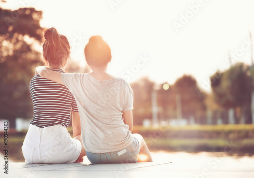 Two women friends resting in the garden, watching the sunshine together happily.