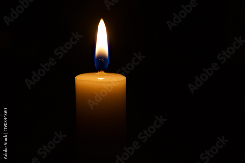 brennende Kerze mit Kerzenschein und schwarzen Hintergrund