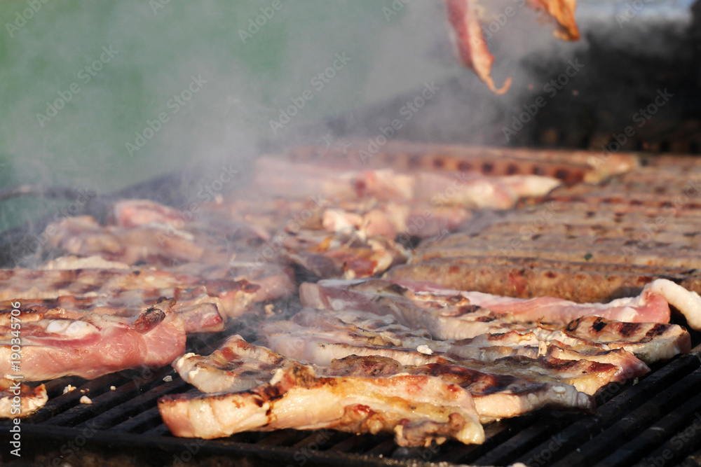 Variety of different kind of meat steaks, meatballs, shish kebab, fillet, burgers and sausages with bread on a grill outdoor. Grilled meat on a barbecue Variety of different kind of meat steaks, meatballs, shish kebab, fillet, burgers and sausages with bread on a grill outdoor. Grilled meat on a barbecue
