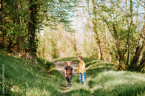 Two funny kids playing together in spring forest, little brother and sister enjoying nice walk in woods © annanahabed