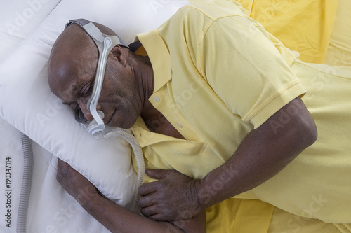 Healthcare concept,African, American Man with obstructive sleep apnea sleeping well with cpap machine ,Man laying in bed wearing cpap mask, on white backgroud