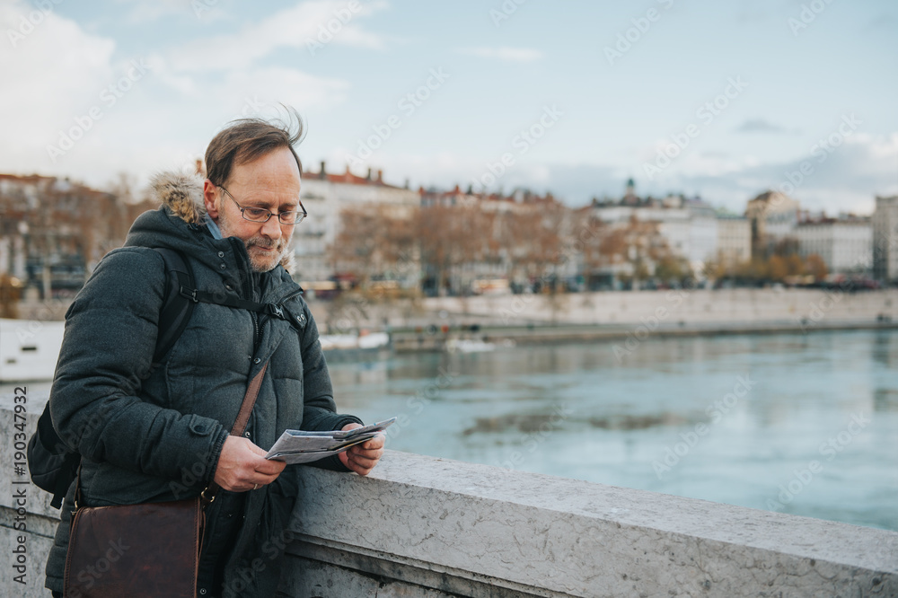 Man tourist with backpack and map admiring Rhone river from Bonaparte Bridge, Lyon, France.