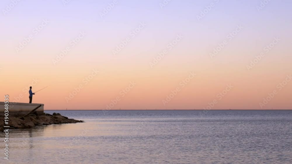 Man fishes alone at a lake during sunset. Man fishes alone at a lake during sunset.