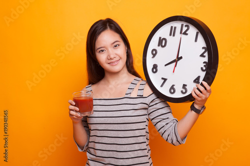 Young Asian woman with tomato juice and clock.