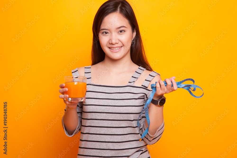Asian woman drink orange juice hold measuring tape. Asian woman drink orange juice hold measuring tape.