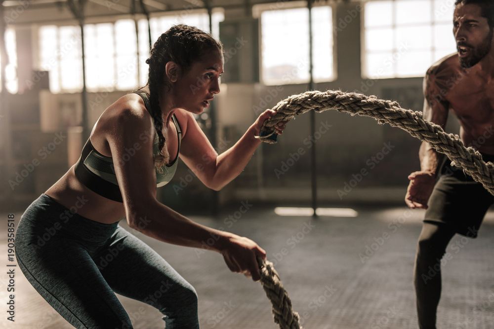 Photo & Art Print Young woman working out with battle ropes