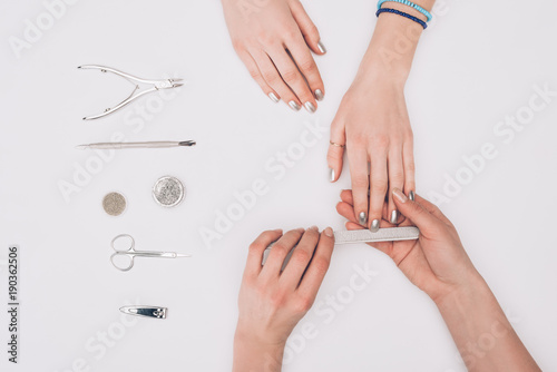 Εκτύπωση καμβά cropped image of manicurist filing nails to customer with nail file isolated on