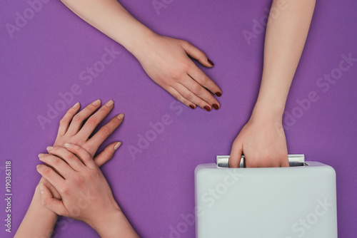 cropped image of customer holding hand in uv lamp isolated on purple