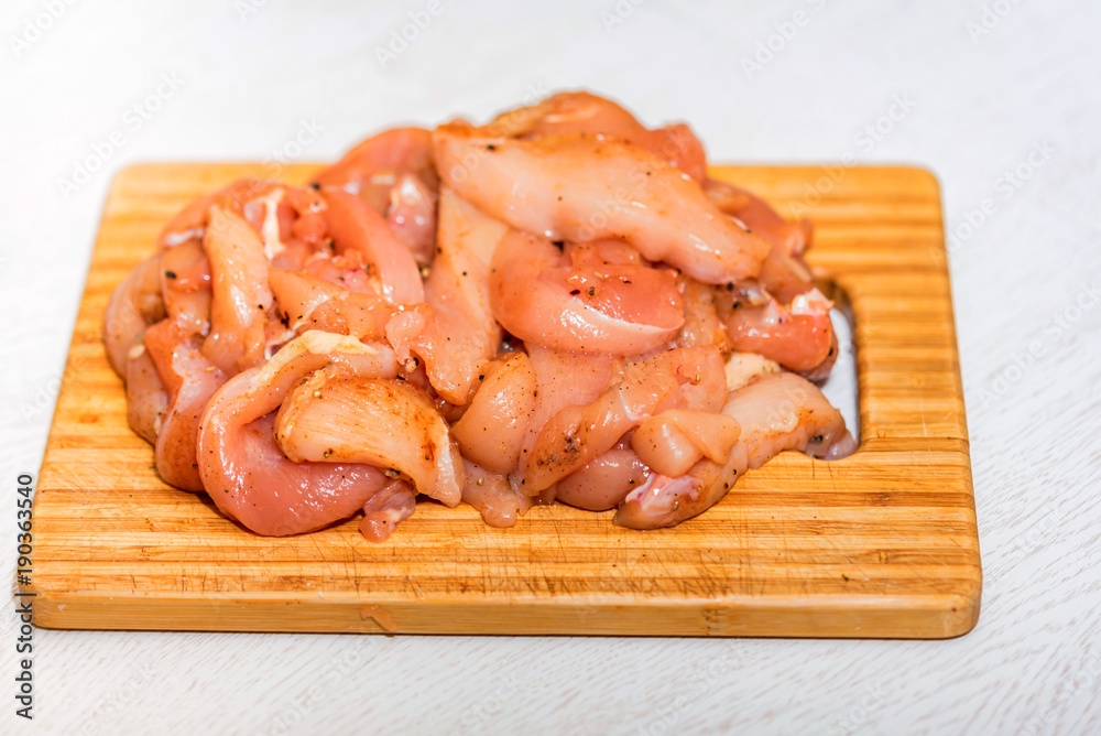 Raw chicken fillet with spices on wooden board Raw chicken fillet with spices on wooden board