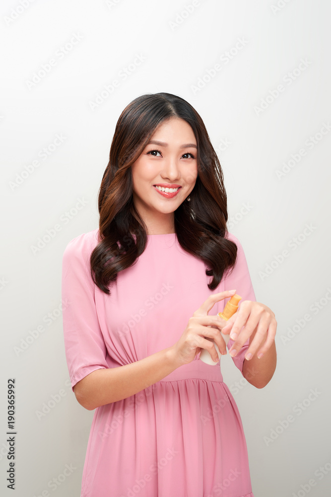 Smiling young asian woman showing skincare product. Smiling young asian woman showing skincare product.
