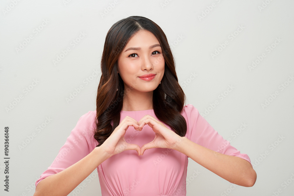 Pretty young asian woman making a heart gesture with her fingers in front of her chest Pretty young asian woman making a heart gesture with her fingers in front of her chest
