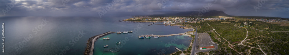 Fototapeta premium Aerial views over Gansbaai harbor in the overberg in the Western Cape of South Africa With fishing vessels laying at anchor in the harbor