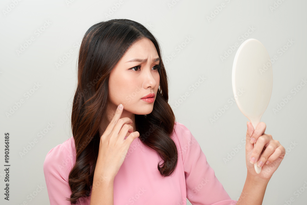 Asian woman looking at the mirror with the trouble on her skin. Asian woman looking at the mirror with the trouble on her skin.