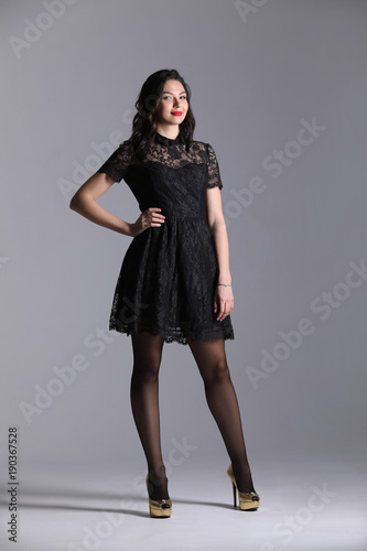 Woman in black dressin studio. Gray background. Photographie retouchee