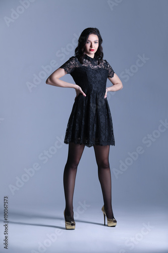 Girl in golden heels with hands on the hips. Gray background. Photographie retouchee