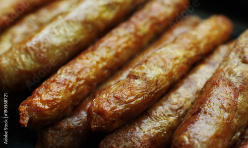 Barbecued meat sausages (bratwurst) close up. Grilled delicious sausages macro shoot.