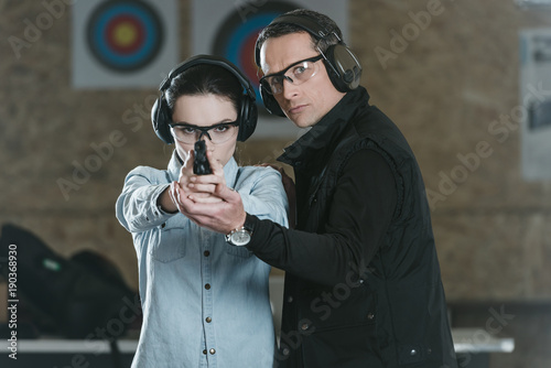 Photography female customer aiming gun at camera in shooting gallery