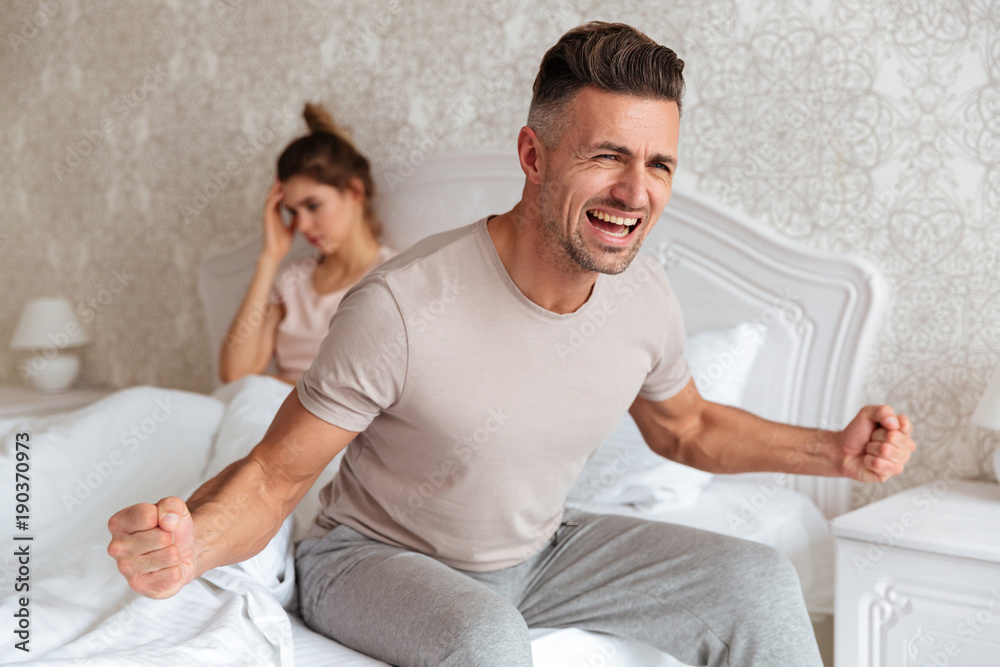 Sad screaming man sitting on bed with his girlfriend Sad screaming man sitting on bed with his girlfriend