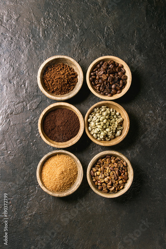 Variety of grounded  instant coffee  different coffee beans  brown sugar in wooden bowls in row over dark texture background. Top view  space