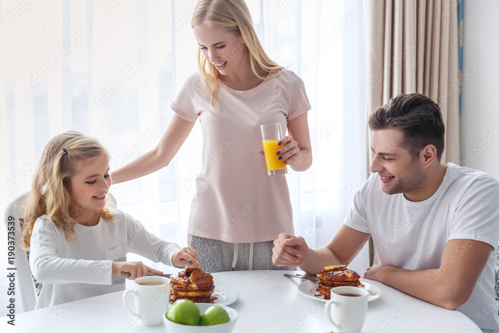 young happy family having breakfast together on weekend morning