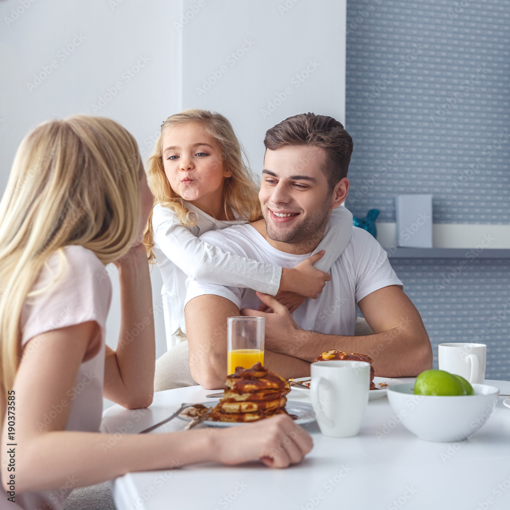 young happy family having breakfast and having fun on weekend morning