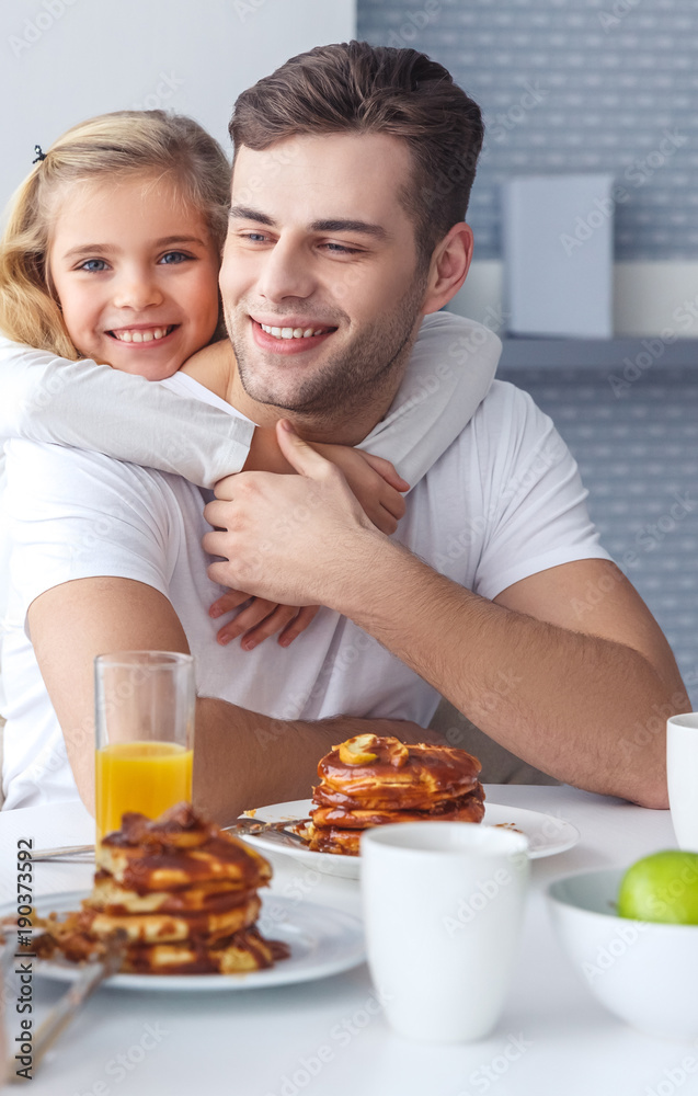 daughter embracing her father from behind while he having breakfast