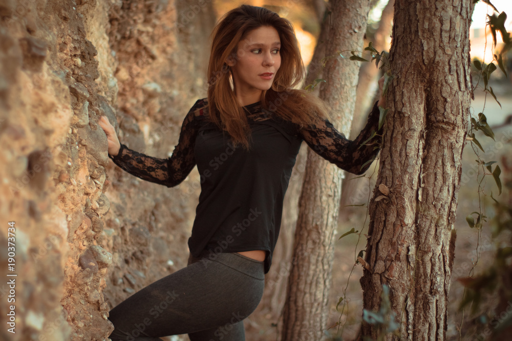 Fotografie Young girl leaning against wall in nature
