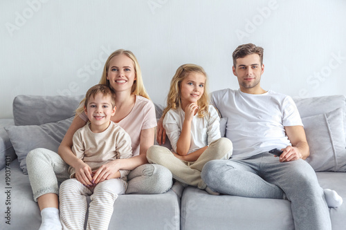 interested young family watching movie on couch at home