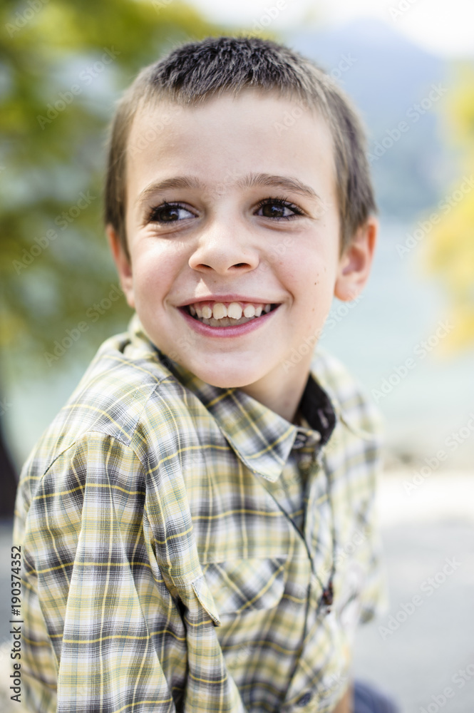 portrait of 9 year old boy smiling with colorful shirt sitting on a wall portrait of 9 year old boy smiling with colorful shirt sitting on a wall