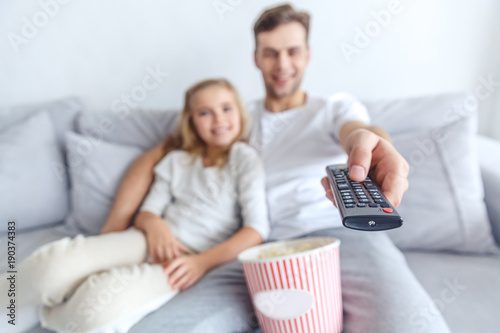 close-up shot of father and daughter using tv remote control at home