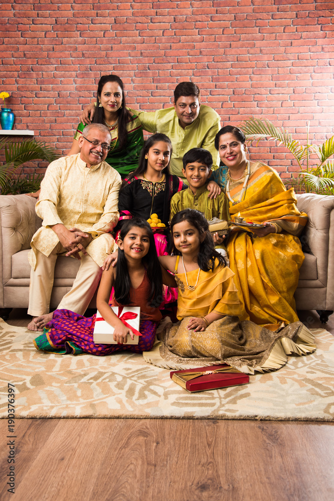 Portrait Of Happy Indian Family In Traditional Wear Sitting On Sofa