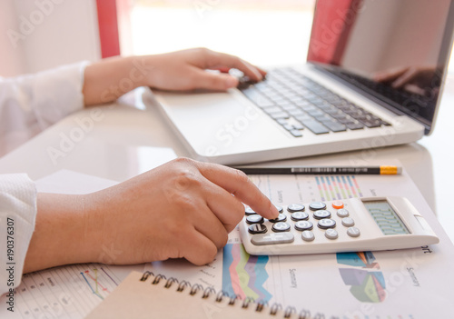 close up business woman hand using calculator and laptop doing counting making at home