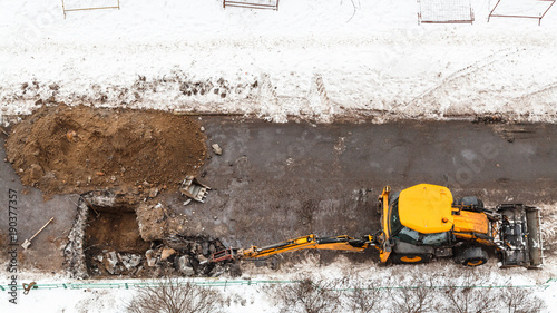 tractor digging road to change sewer pipes photo