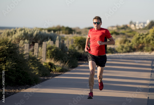 young attractive and happy sport runner man with fit and strong healthy body training on off road track in Summer running workout