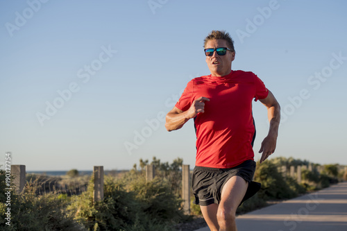 Fototapeta Naklejka Na Ścianę i Meble -  young attractive and happy sport runner man with fit and strong healthy body training on off road track in Summer running workout