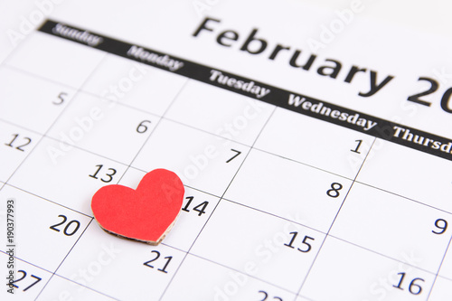 Calendar page and red hearts paper on February 14 of Valentines day.