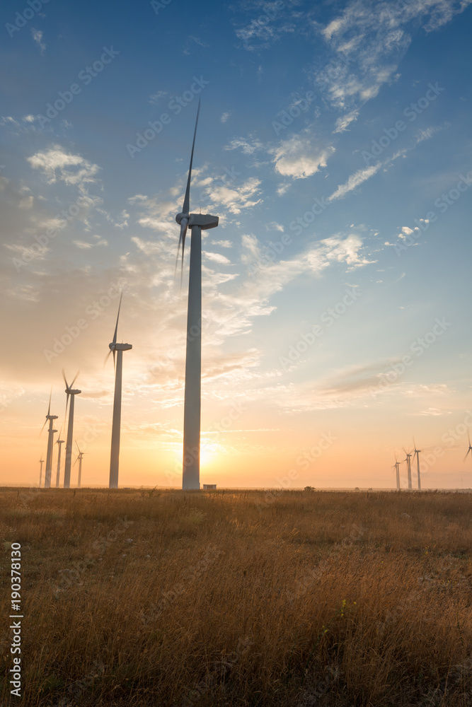 Obraz premium Wind turbines against red, blue and orange sunrise